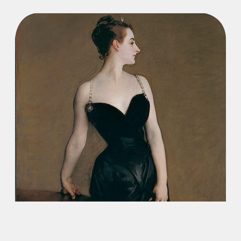 A woman in a black dress poses her right hand on a table and glances slightly over her shoulder.